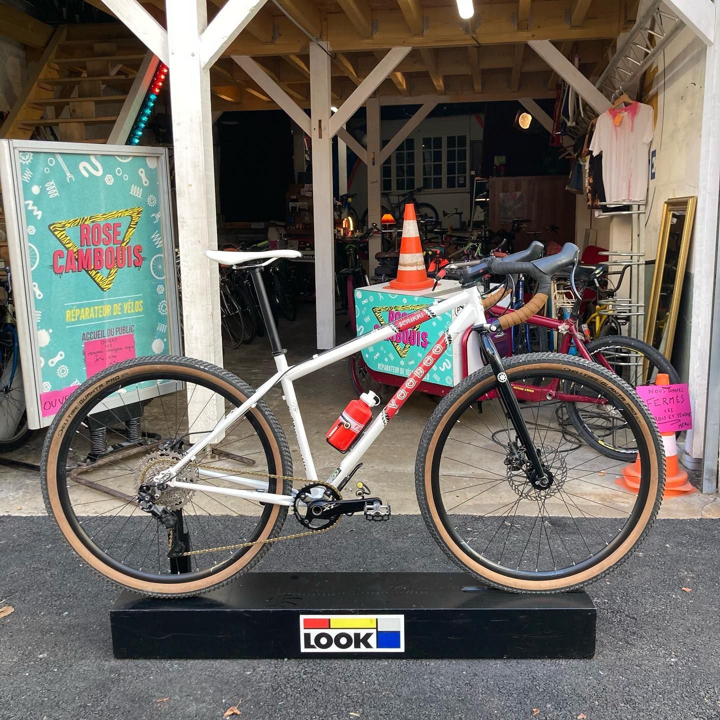 Devanture de l'atelier Rose Cambouis : un vélo exposé devant le panneau rose et turquoise