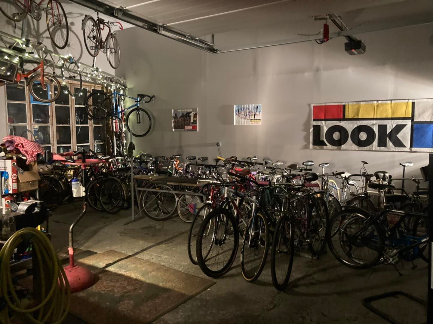 Intérieur de l'atelier : des dizaines de vélos alignés, vélos anciens accrochés au plafond